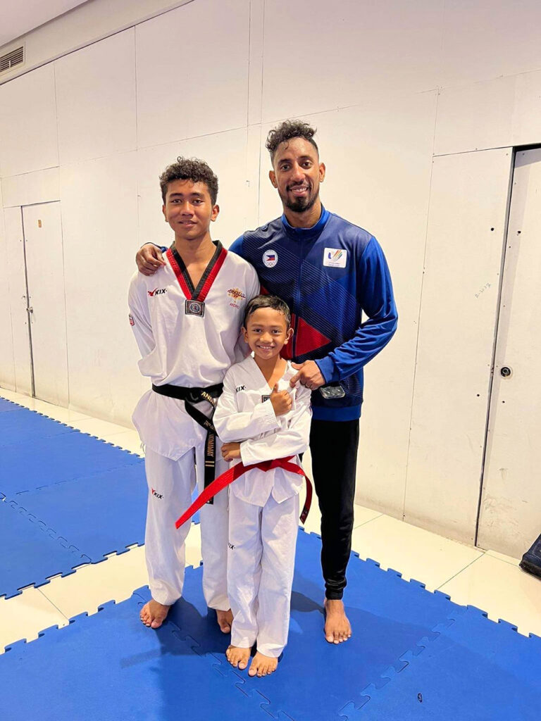 The brothers Andrei Jade and Denzel Jade Domamay, with coach Butch Morrison, world championship taekwondo gold medalist.